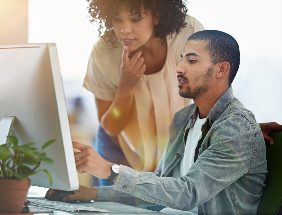 Two marketers working on an interactive video on a computer in a bright and modern office. 