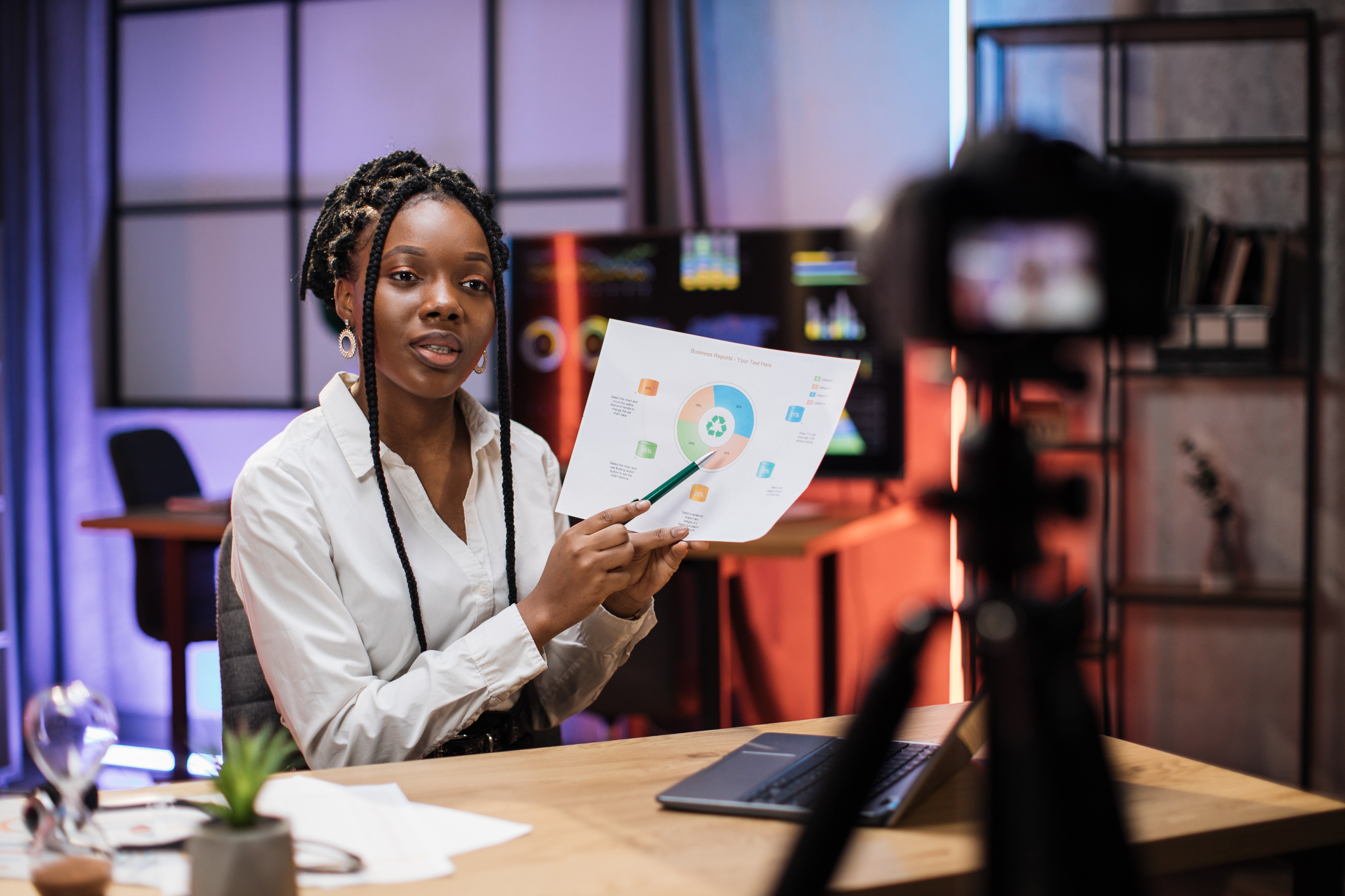 African businesswoman in a formal suit presenting a marketing strategy chart on camera in a modern office setting. (1)