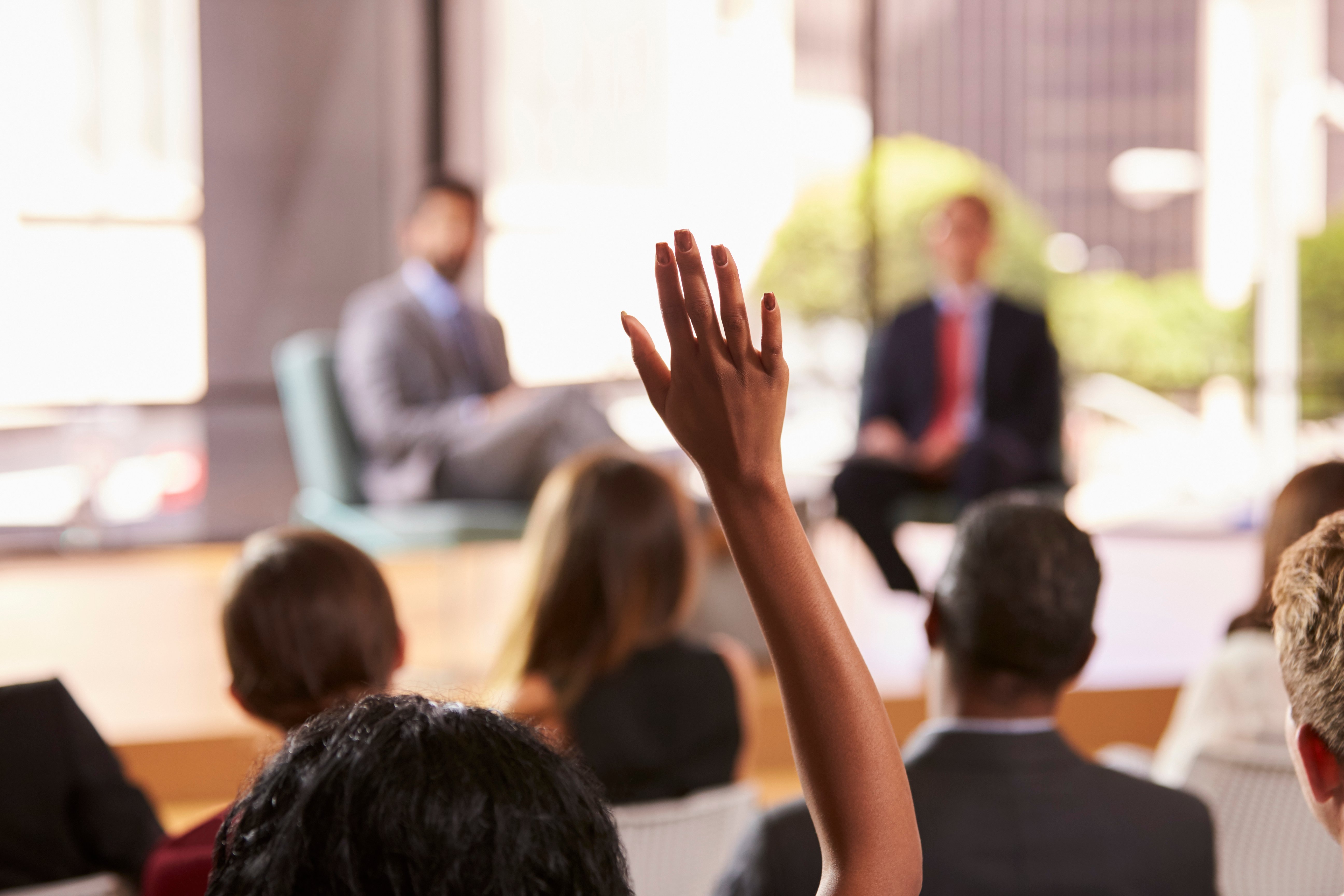 An audience member raises their hand to ask a question during a panel discussion on the They Ask, You Answer strategy, focused on the medical device industry