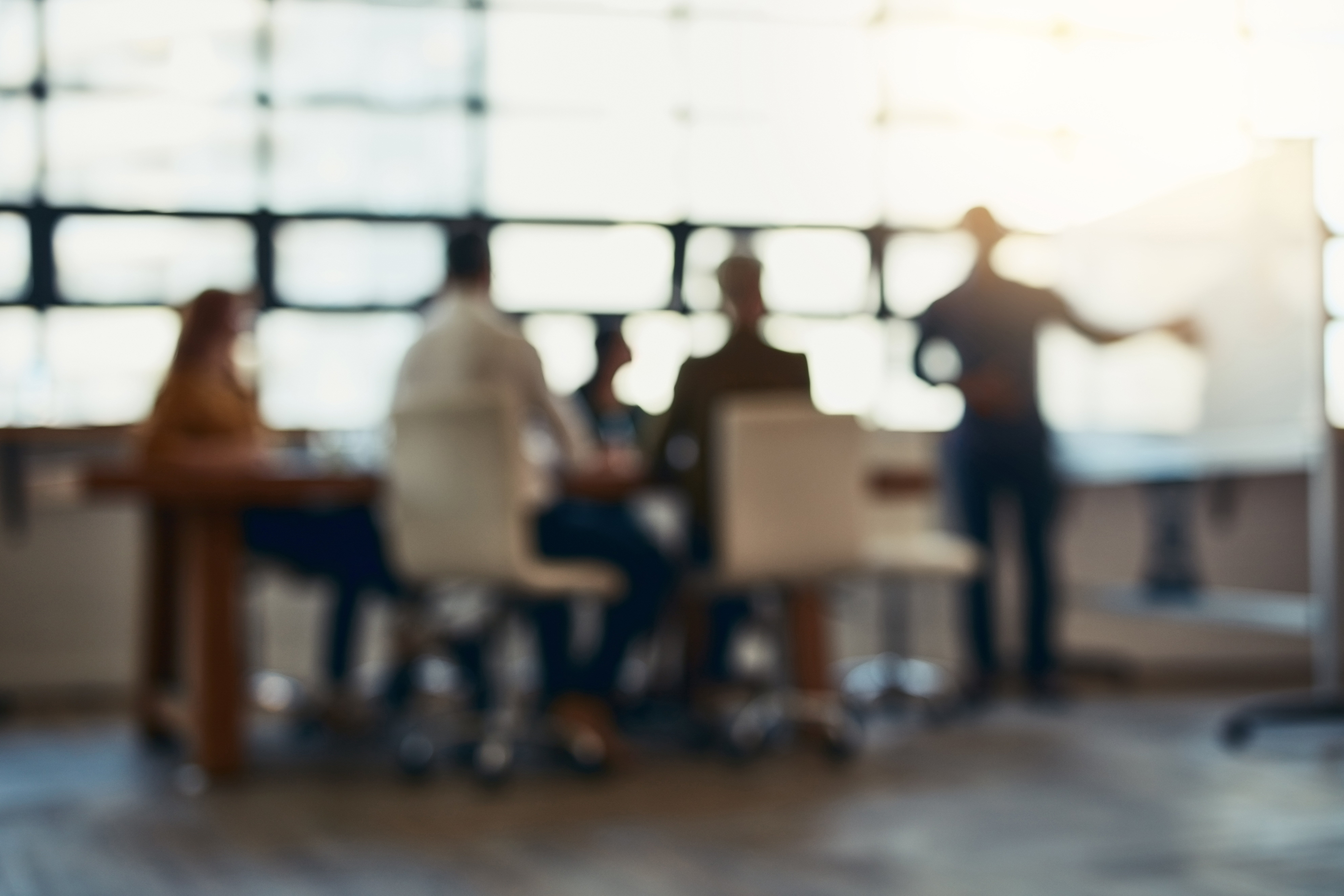 Blurry view of a team in a meeting, discussing the onboarding process for a medical device marketing strategy in a bright, modern office. 