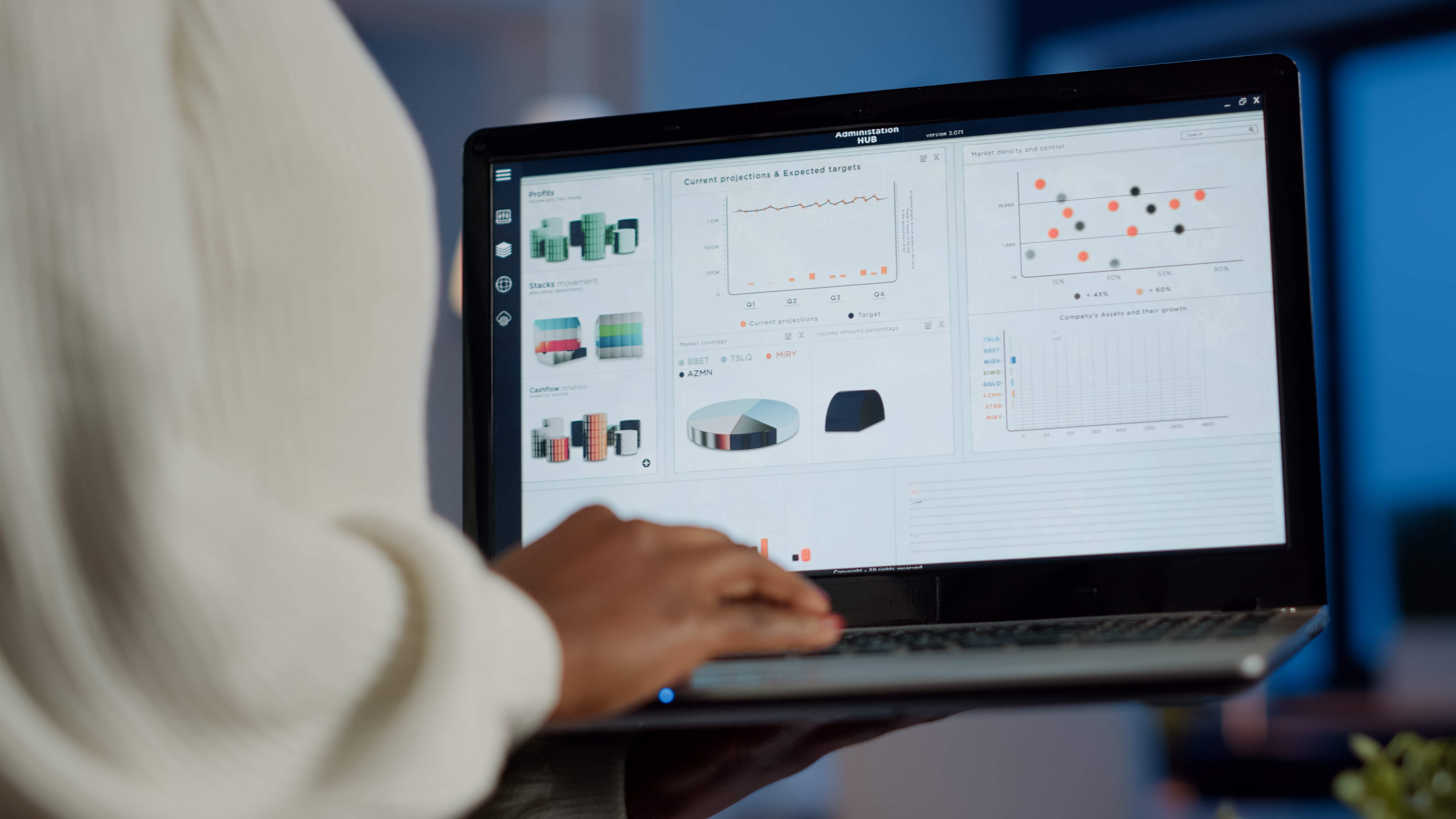 Close-up of a person holding a laptop, analysing financial data and charts displayed on the screen