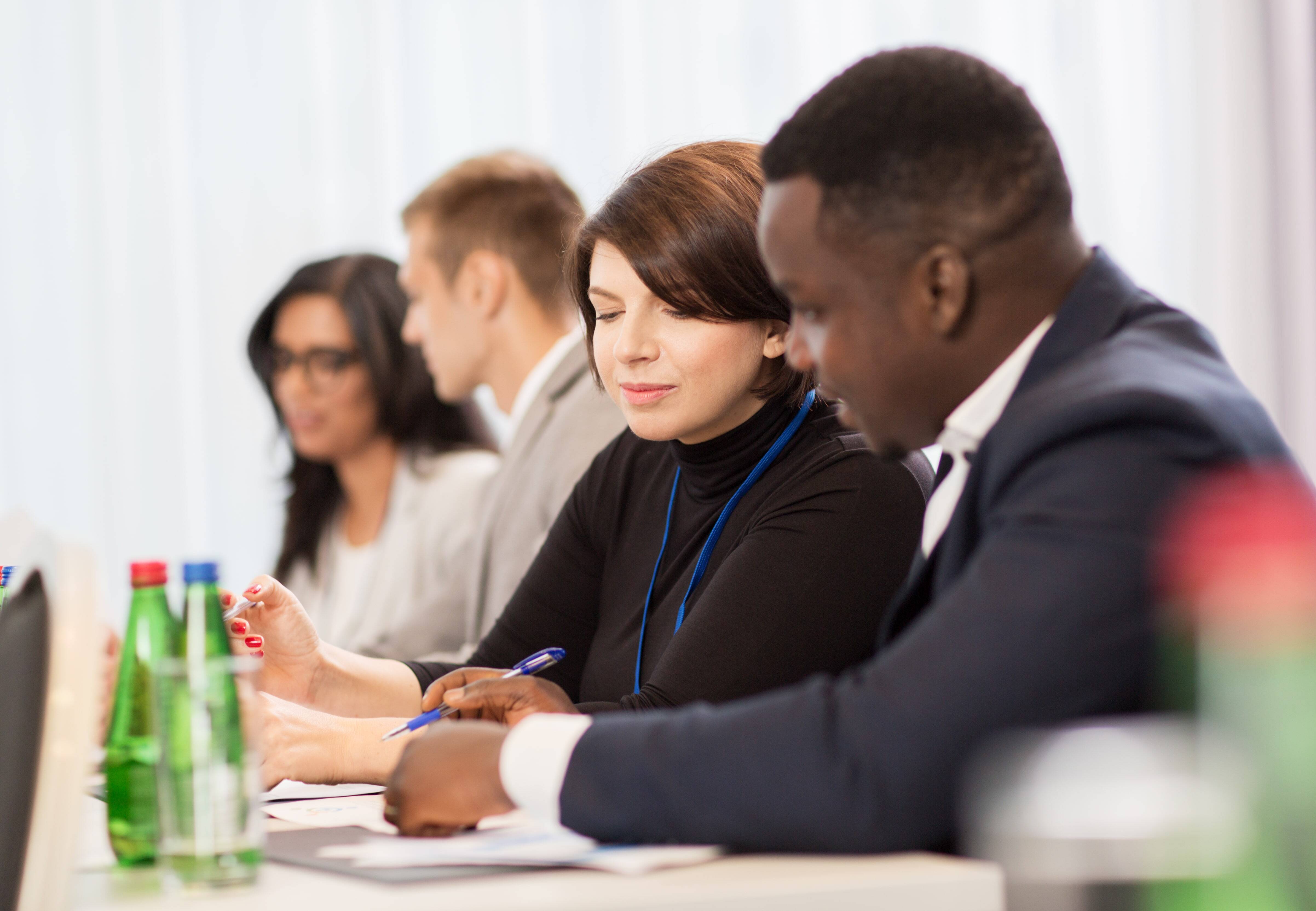 Diverse group of business professionals sitting at a conference table, engaged in discussion during an international meeting.