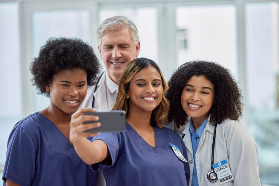 Medical professionals smiling and taking a selfie with a smartphone