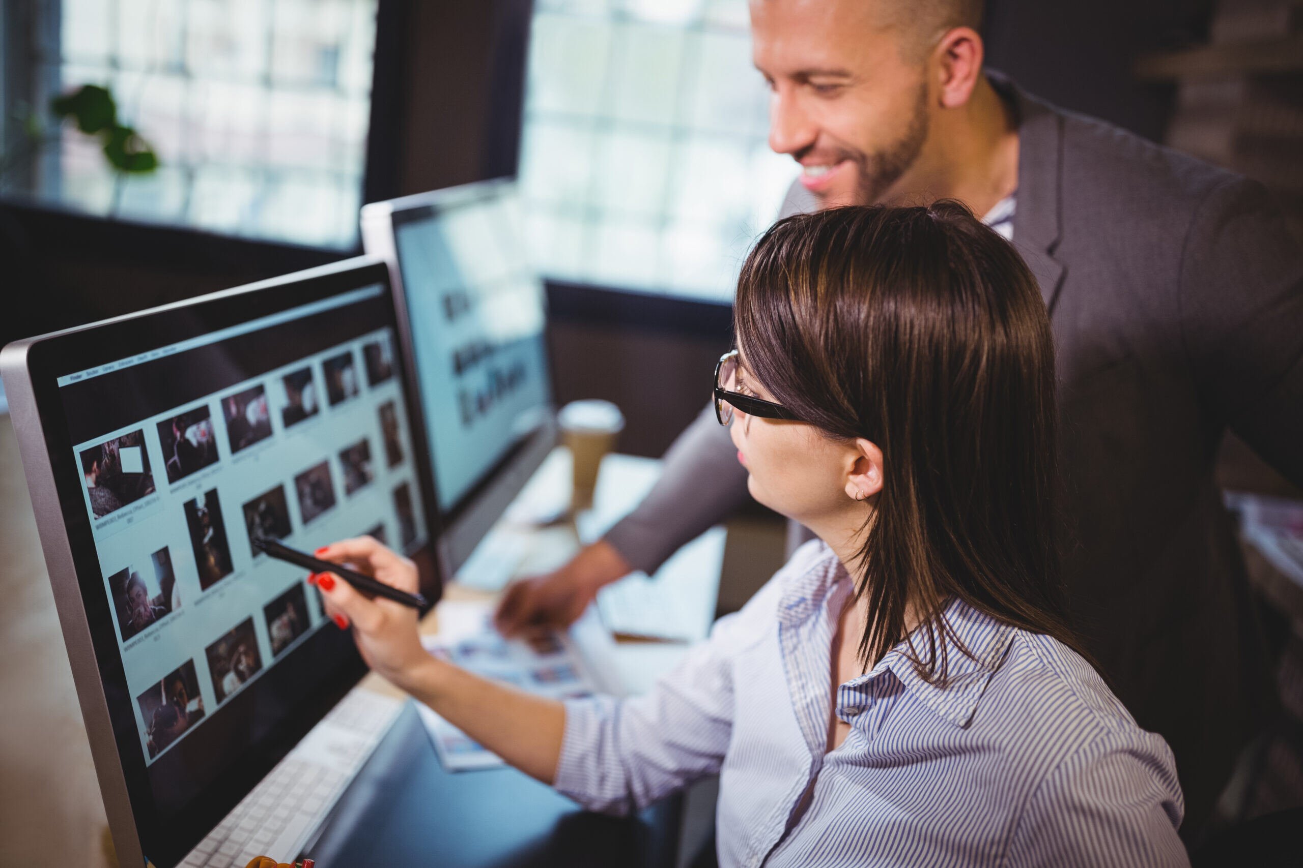 Graphic designer and marketer working on social media posts together on a computer