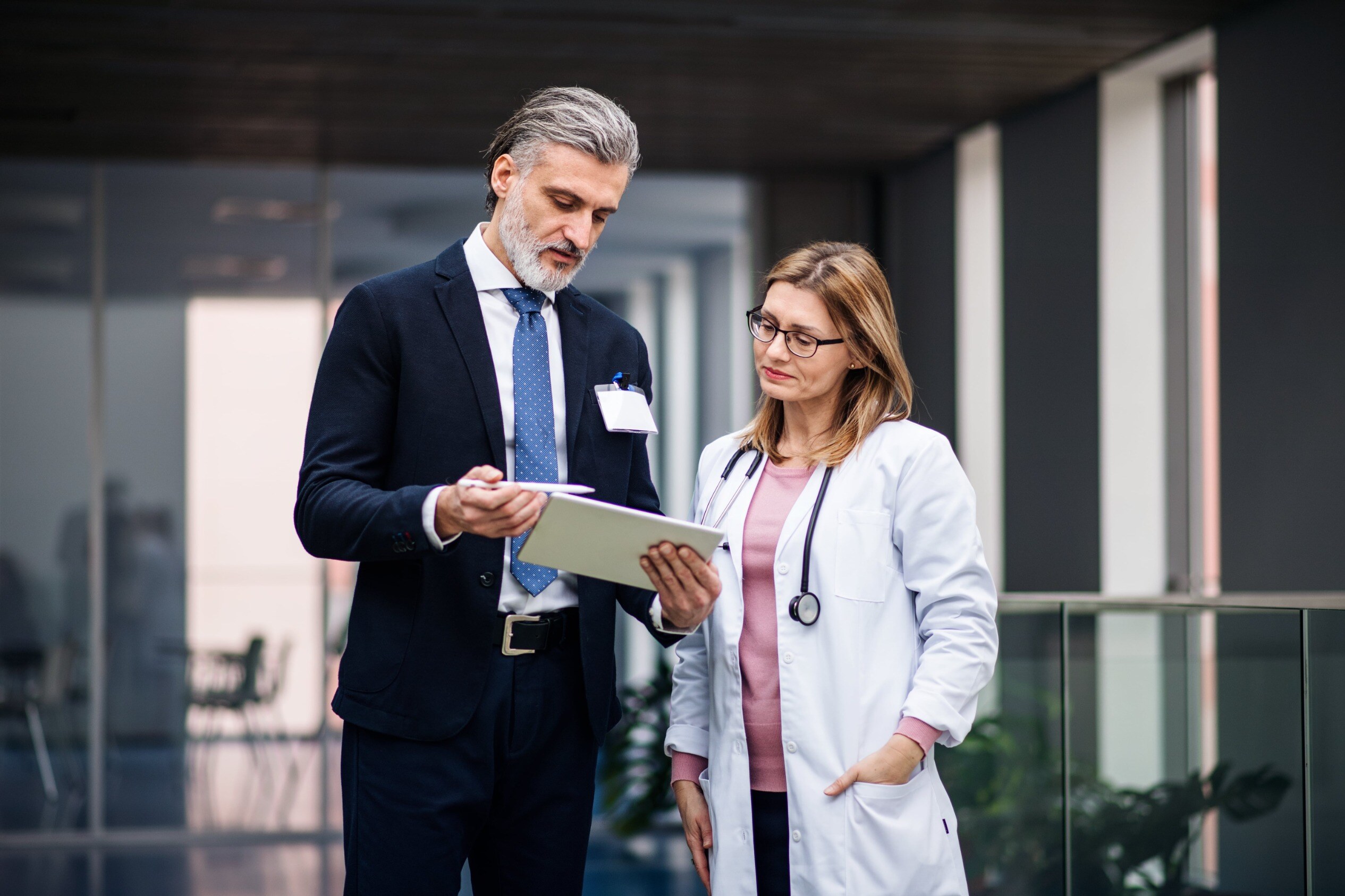 A medical device sales rep shows his website to a HCP on a tablet.