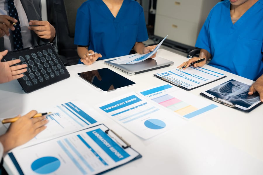 Medical device sales team reviewing printed out reports from CRM