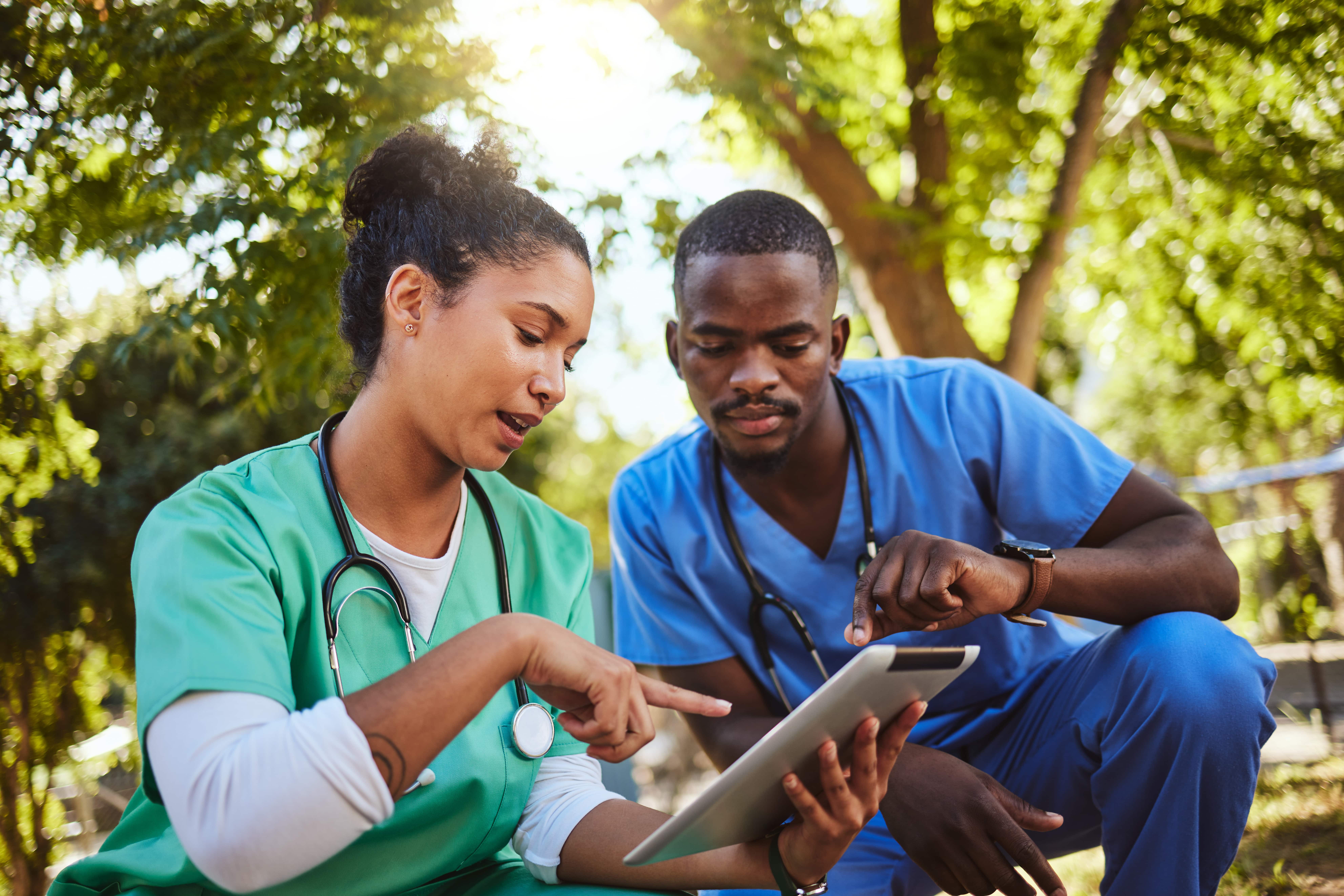 two healthcare professionals looking at social media on a tablet