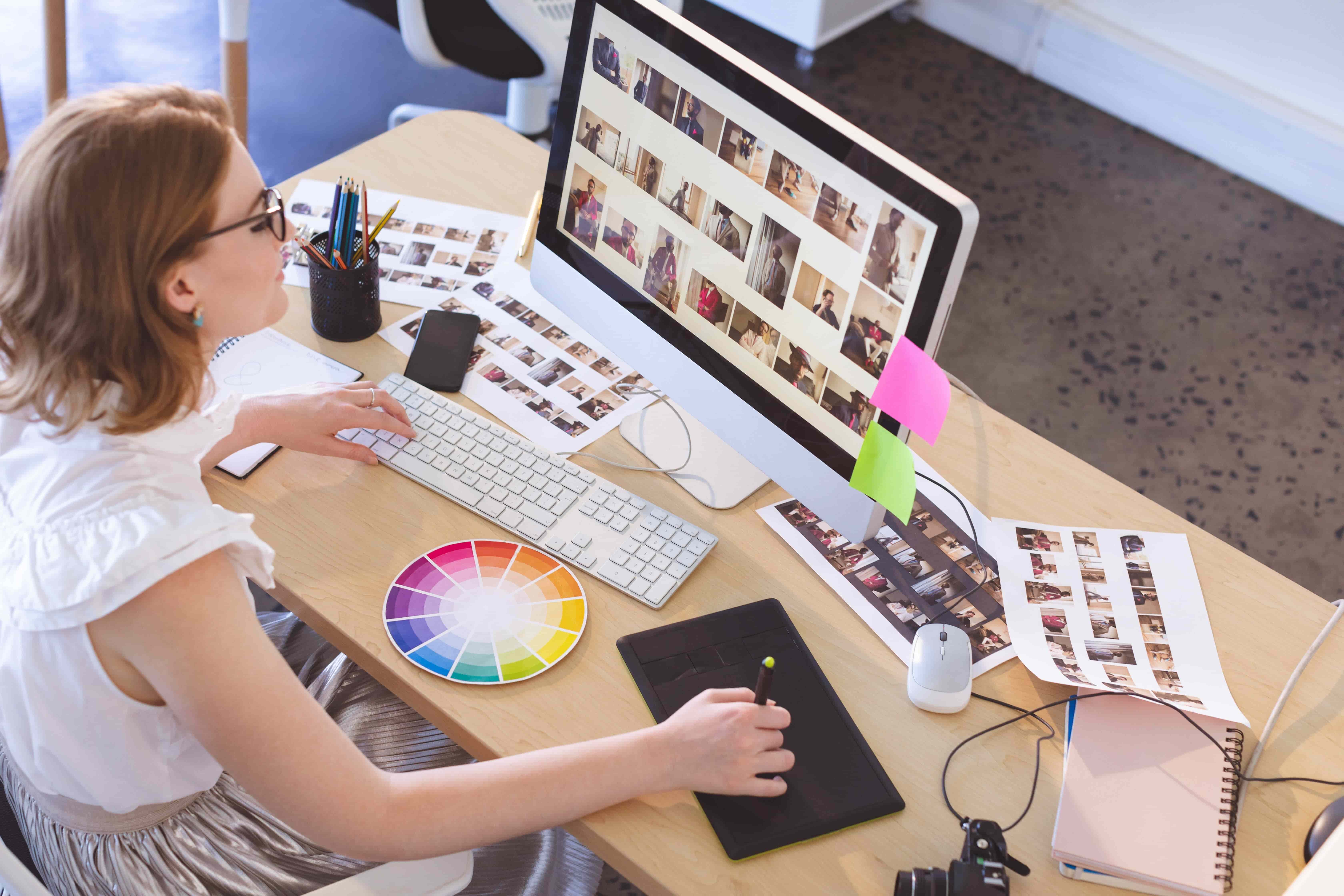A female graphic designer working on a project and using a colour wheel to help her.