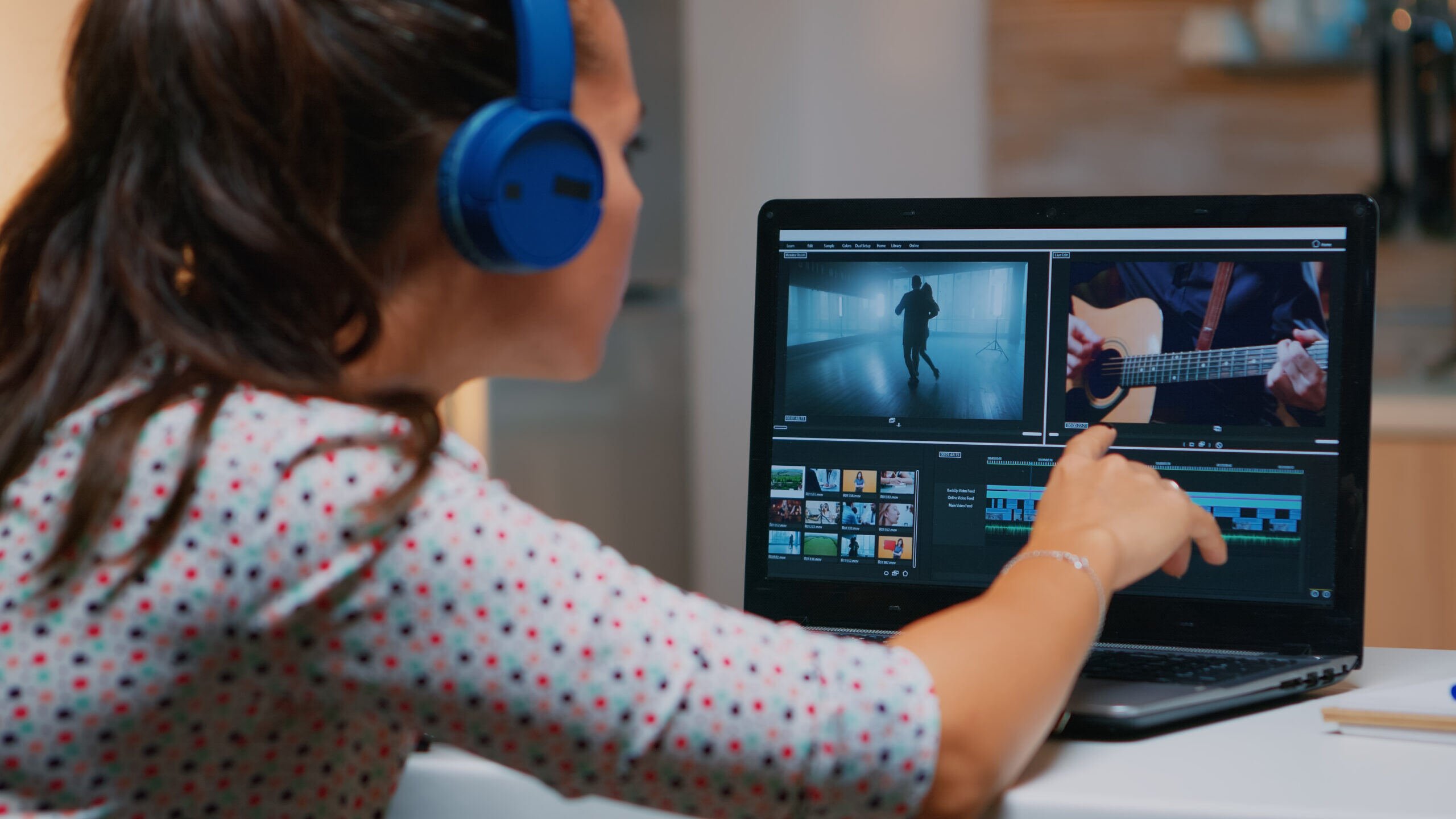 Woman with blue headphones watching video on computer.
